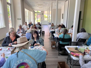 large room of people all at tables doing collage